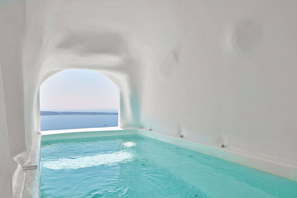 A clear view of a swimming pool with a view of the sea through an arched window.