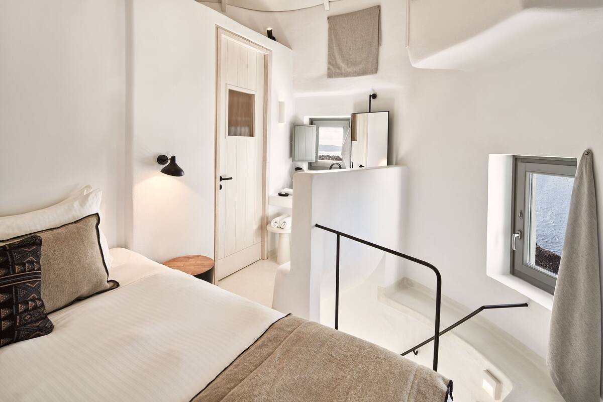 A modern bedroom with a bed, bedside table, and a window with a view.