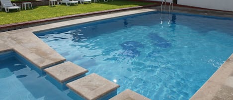 Alberca al aire libre y camastros