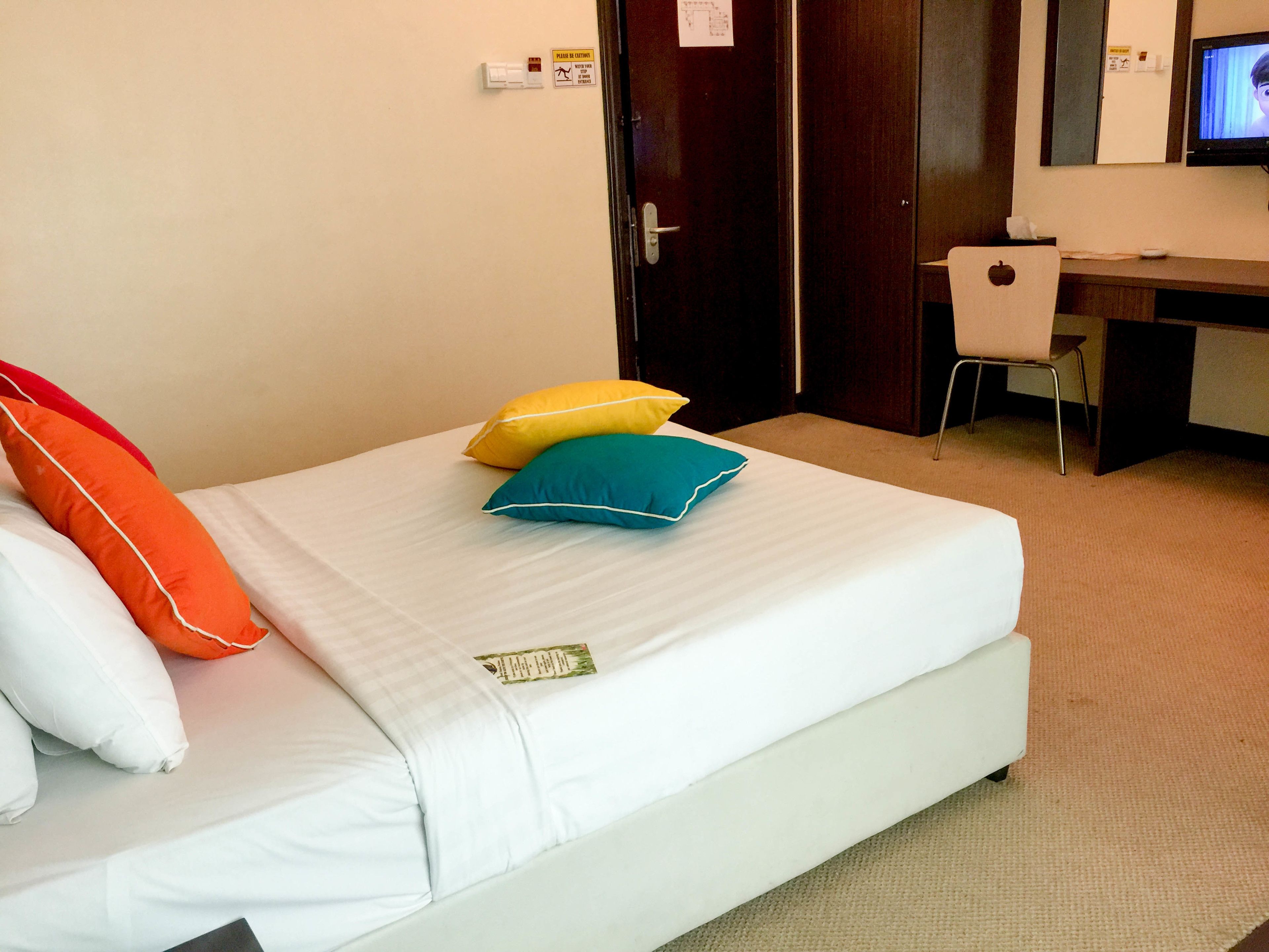 A hotel room with a bed, a desk, and a television.