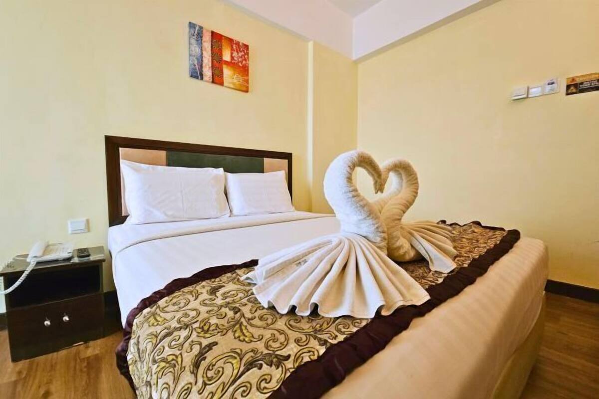 A hotel room with a bed, a nightstand, and a wall-mounted artwork.