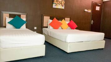 Dos camas dobles con ropa de cama blanca y almohadas coloridas, un cuadro en la pared y una puerta con un letrero.