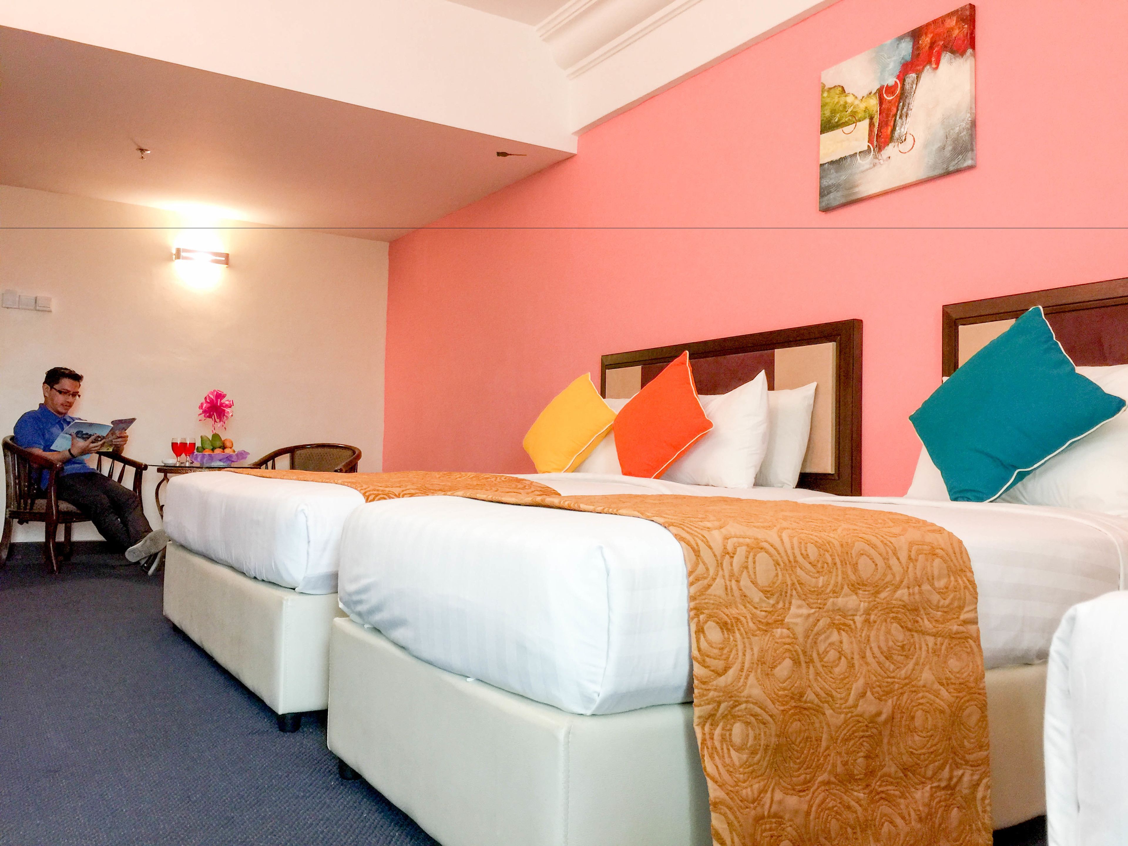 Une chambre d’hôtel avec deux lits, une petite table avec une chaise et un tableau au mur.