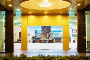 Un hall de hotel con mostrador de recepción, una araña y un diseño moderno.