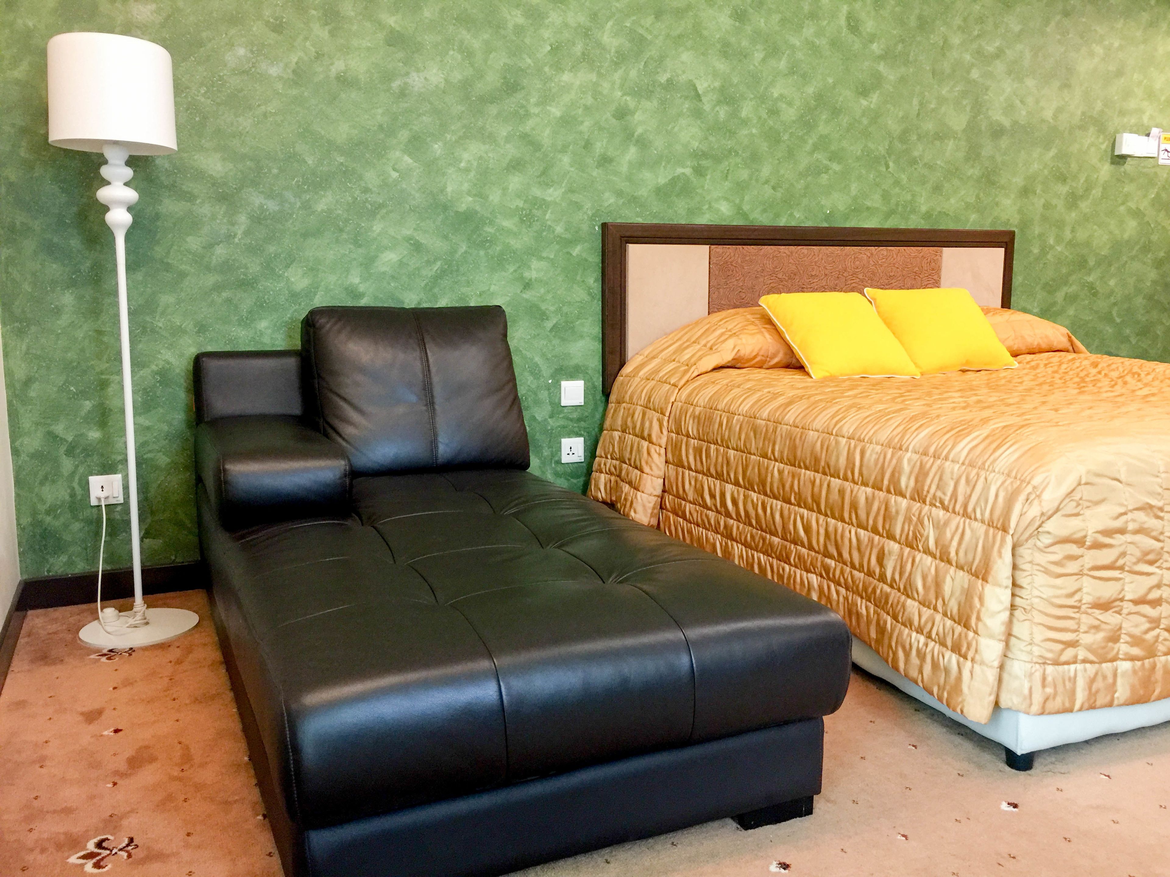 Una stanza con un letto, un divano e una lampada da terra.