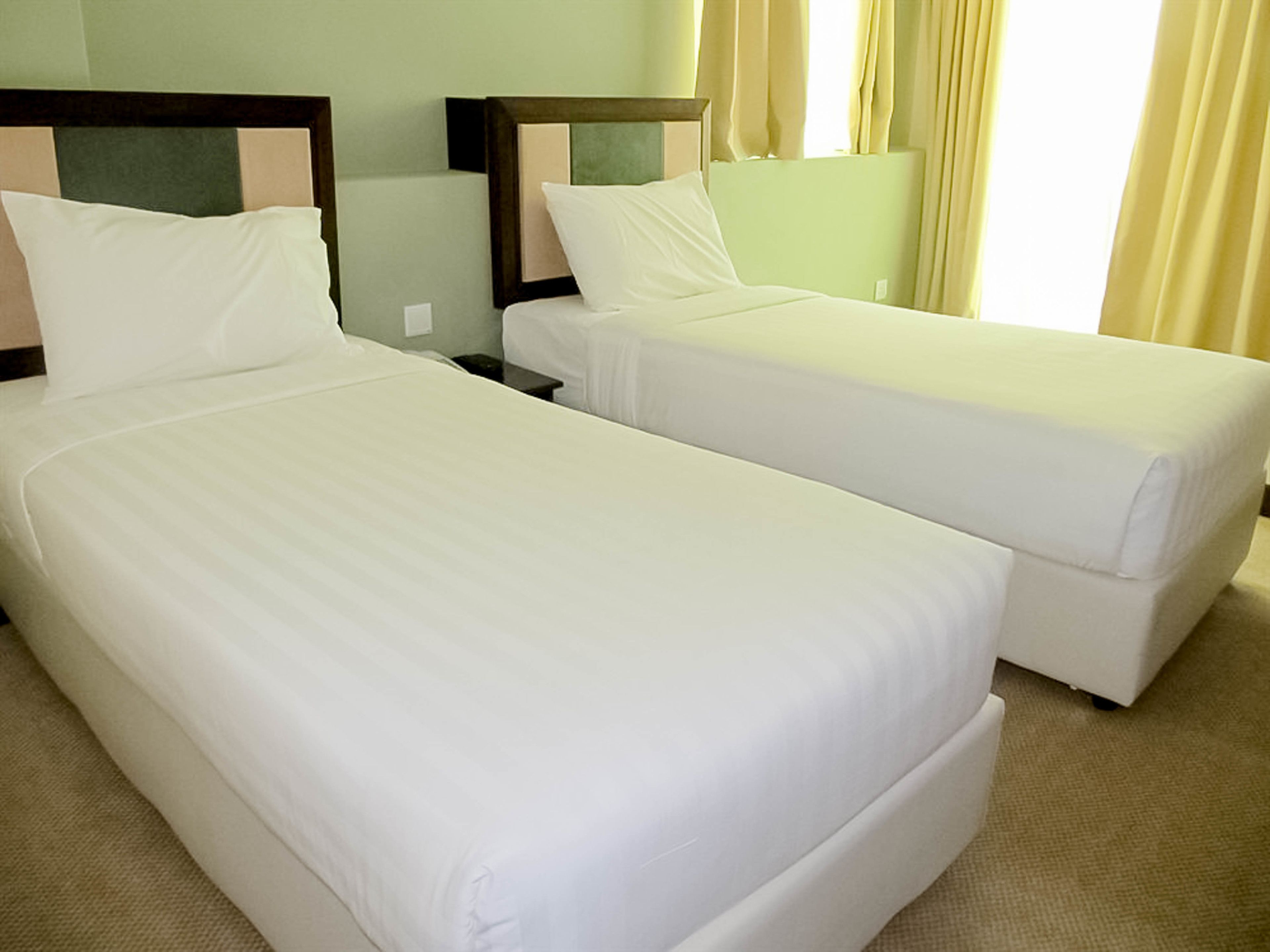 Two single beds with wooden headboards in a hotel room.