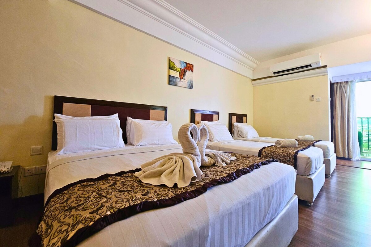 Una habitación de hotel con tres camas, un ventanal con cortinas y un cuadro en la pared.