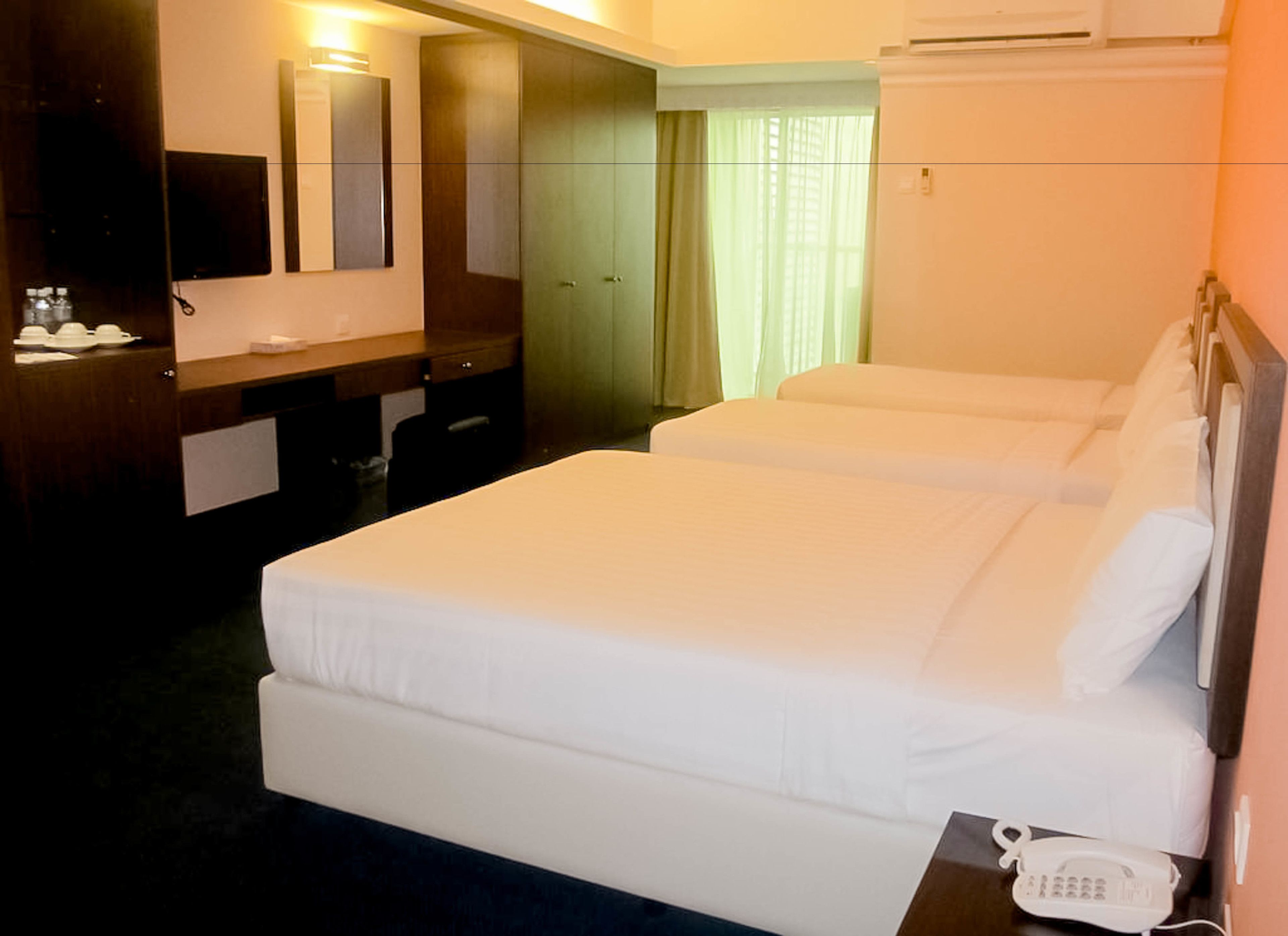 A hotel room with two single beds, a desk with a telephone, a mirror, and a wardrobe.