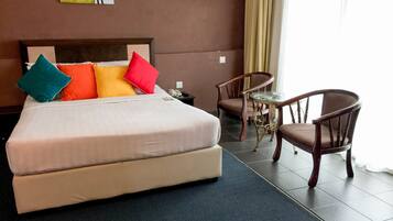 Une chambre d’hôtel avec un lit, deux chaises, une petite table et un tableau au mur.