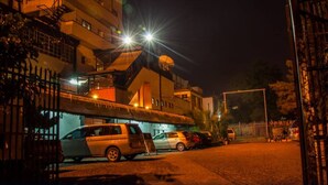 A nighttime street view with a building featuring a sloped roof and multiple balconies. There are parked cars and a gated entrance. - Kahama Hotel (Nairobi)