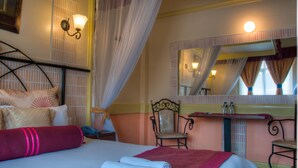 A hotel room with a bed, a chair, a vanity with a mirror, and a nightstand. - Kahama Hotel (Nairobi)