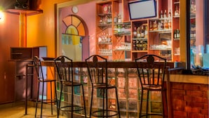 A bar area with a brick wall, a television, and shelves stocked with bottles and glasses. - Kahama Hotel (Nairobi)