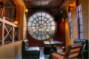 A restaurant with a large circular window, cushioned seating, and a small table with a vase. - Kahama Hotel (Nairobi)