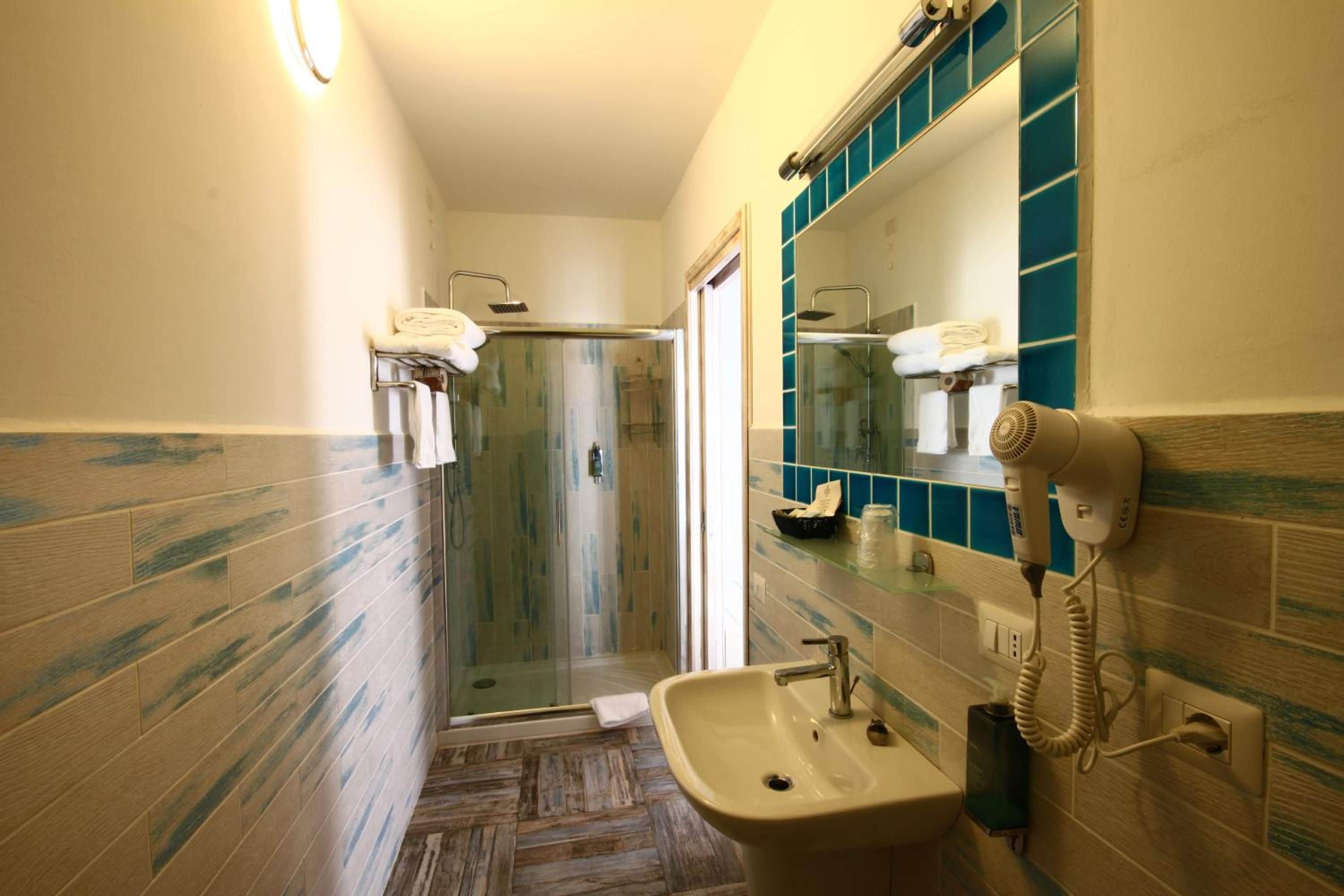 Een badkamer met een douche, een wastafel en een haardroger aan de muur.