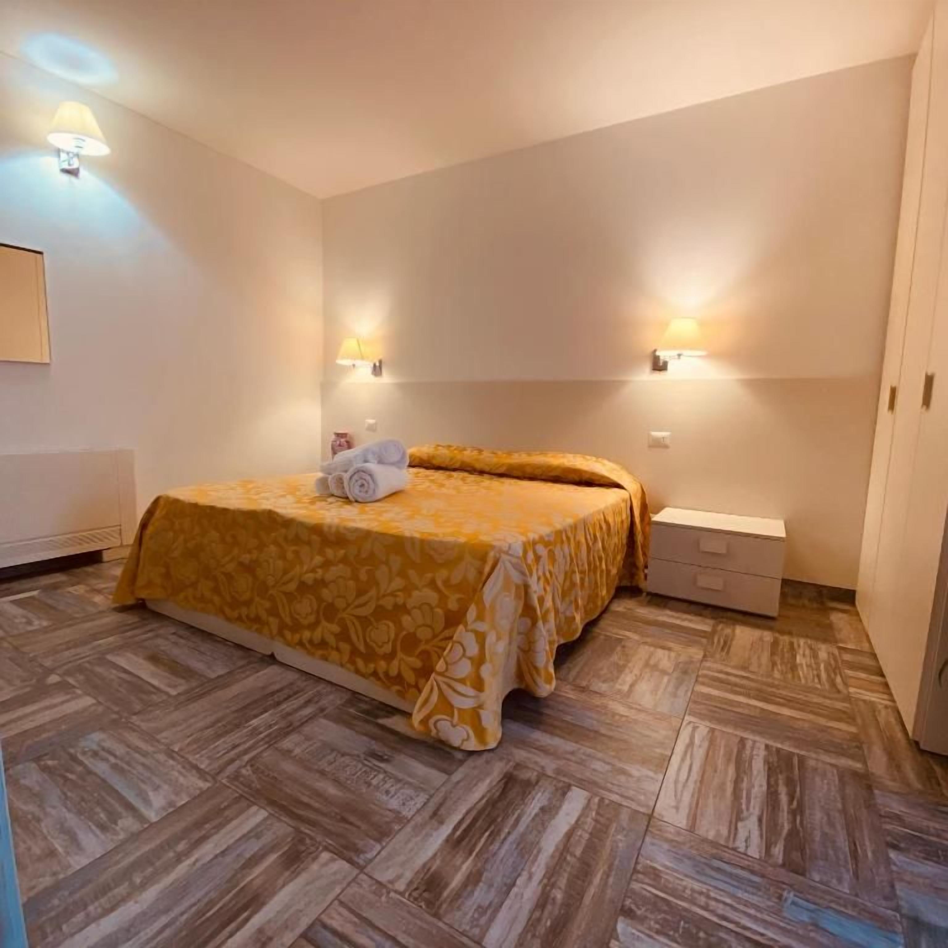 Una camera da letto con un letto, due lampade a parete, un comodino e un settimino.