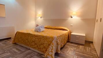 A bedroom with a bed, two wall-mounted lamps, a bedside table, and a chest of drawers.