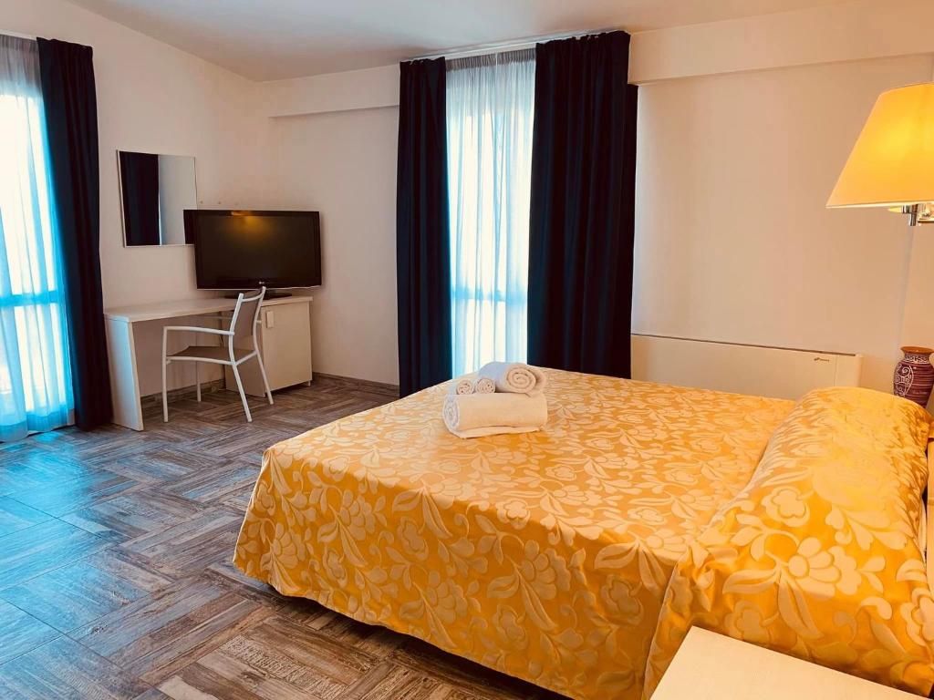 Une chambre d’hôtel avec un lit, un bureau, une télévision et une lampe.