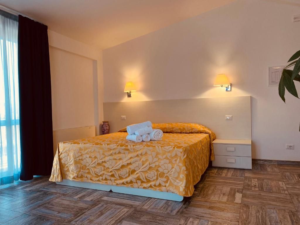 Ein Hotelzimmer mit einem Bett, Nachttischlampen, einem Nachttisch und einer Zimmerpflanze.