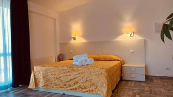 Ein Hotelzimmer mit einem Bett, Nachttischlampen, einem Nachttisch und einer Zimmerpflanze.