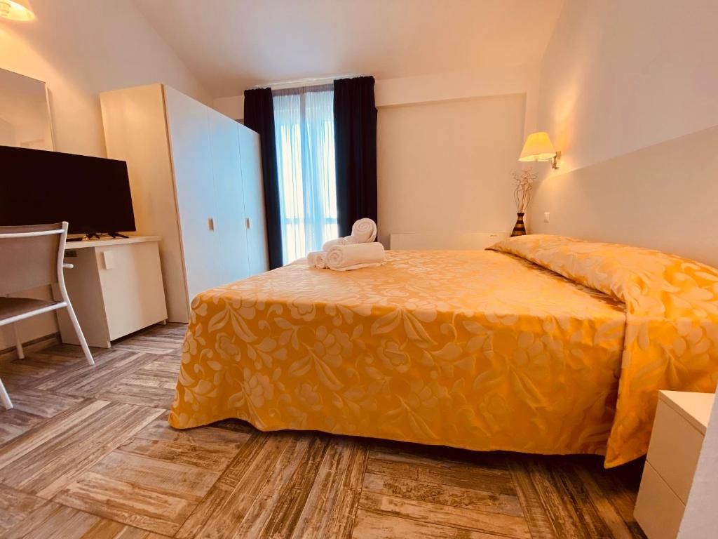 Une chambre d’hôtel avec un lit, un bureau, une télévision et une fenêtre avec des rideaux.