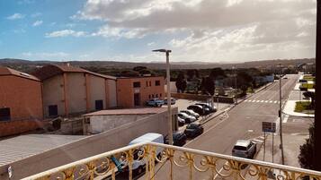 Vista de la calle con coches estacionados, edificios y cielo despejado.