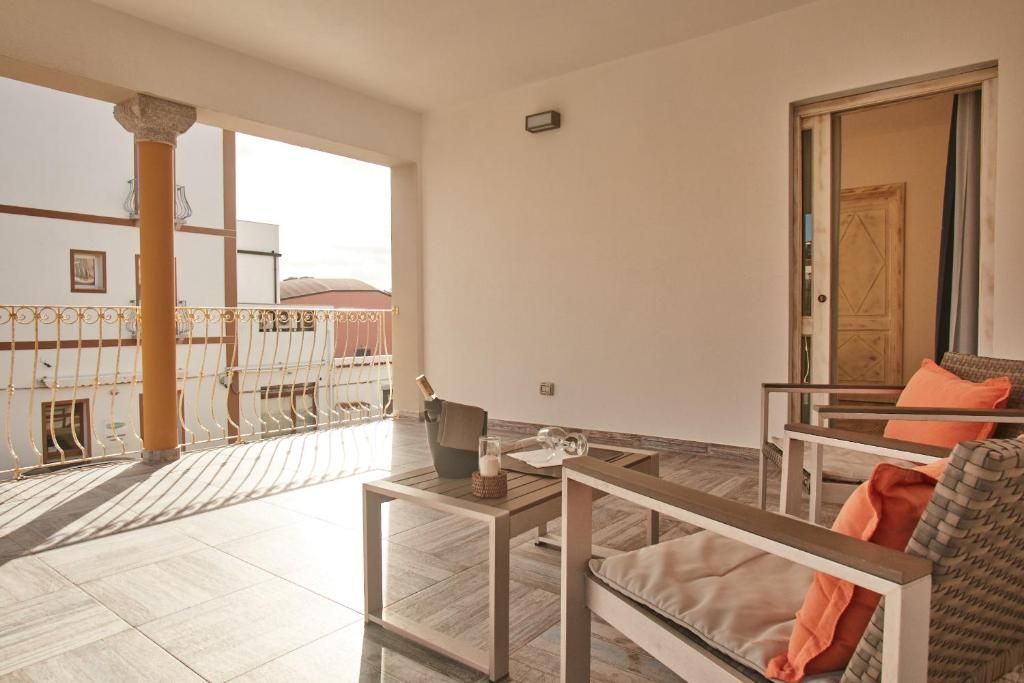 A spacious living area with a balcony, a wooden table, and a sofa with cushions.