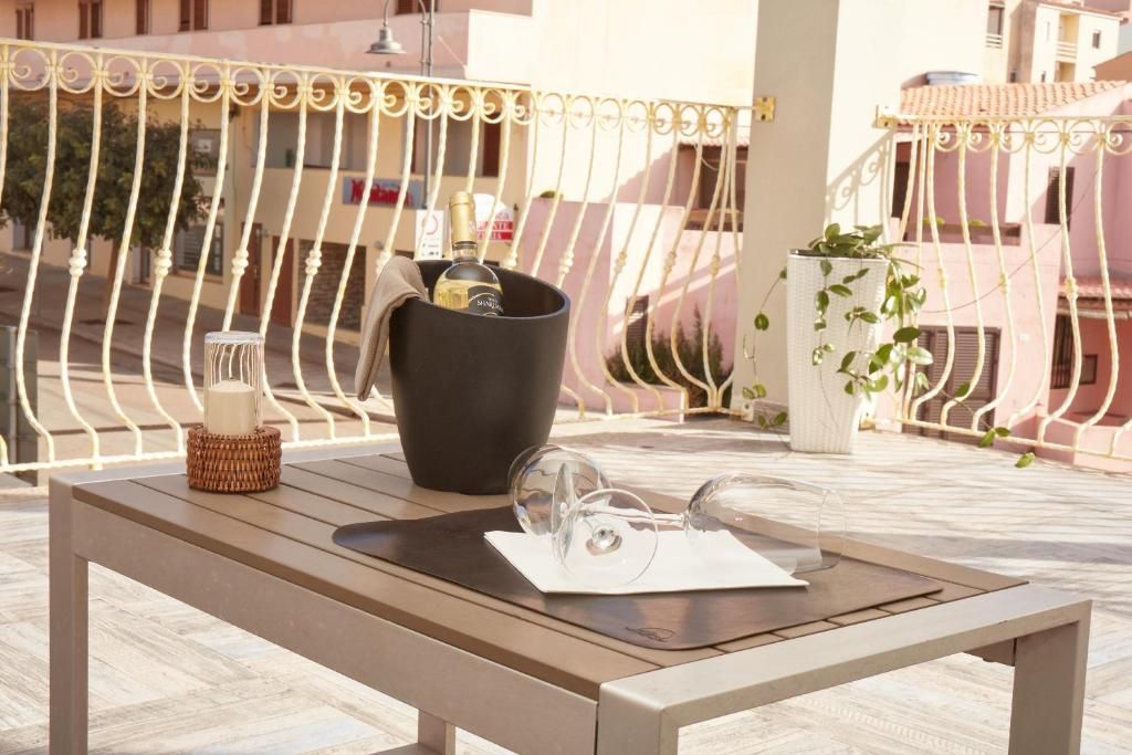 Una mesa de madera con un balde negro, una botella y un par de gafas en una terraza con baranda de metal.