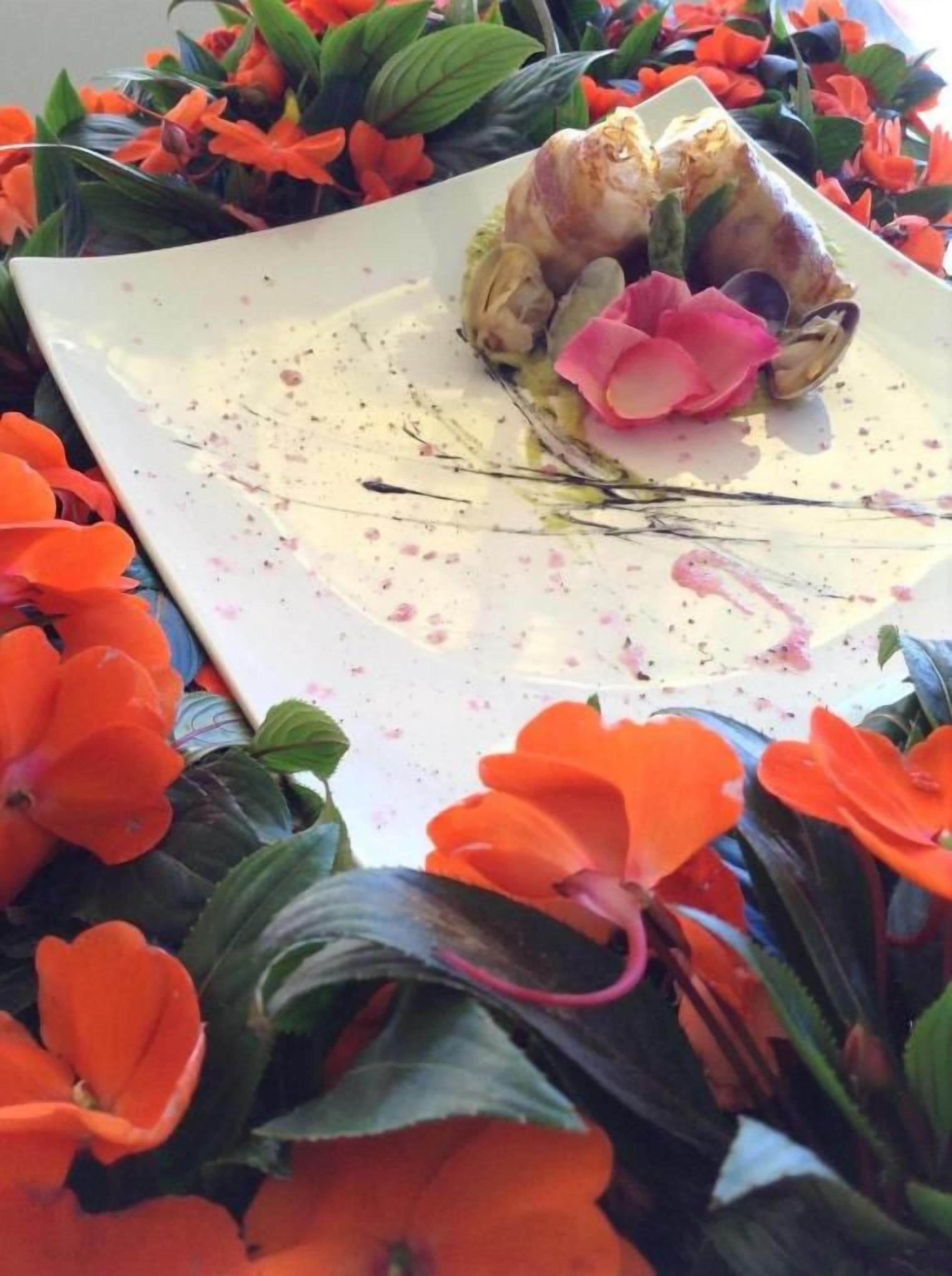 A dessert on a white plate with a floral arrangement around it.