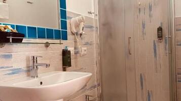 Un baño con cabina de ducha de vidrio, lavamanos y bidé.