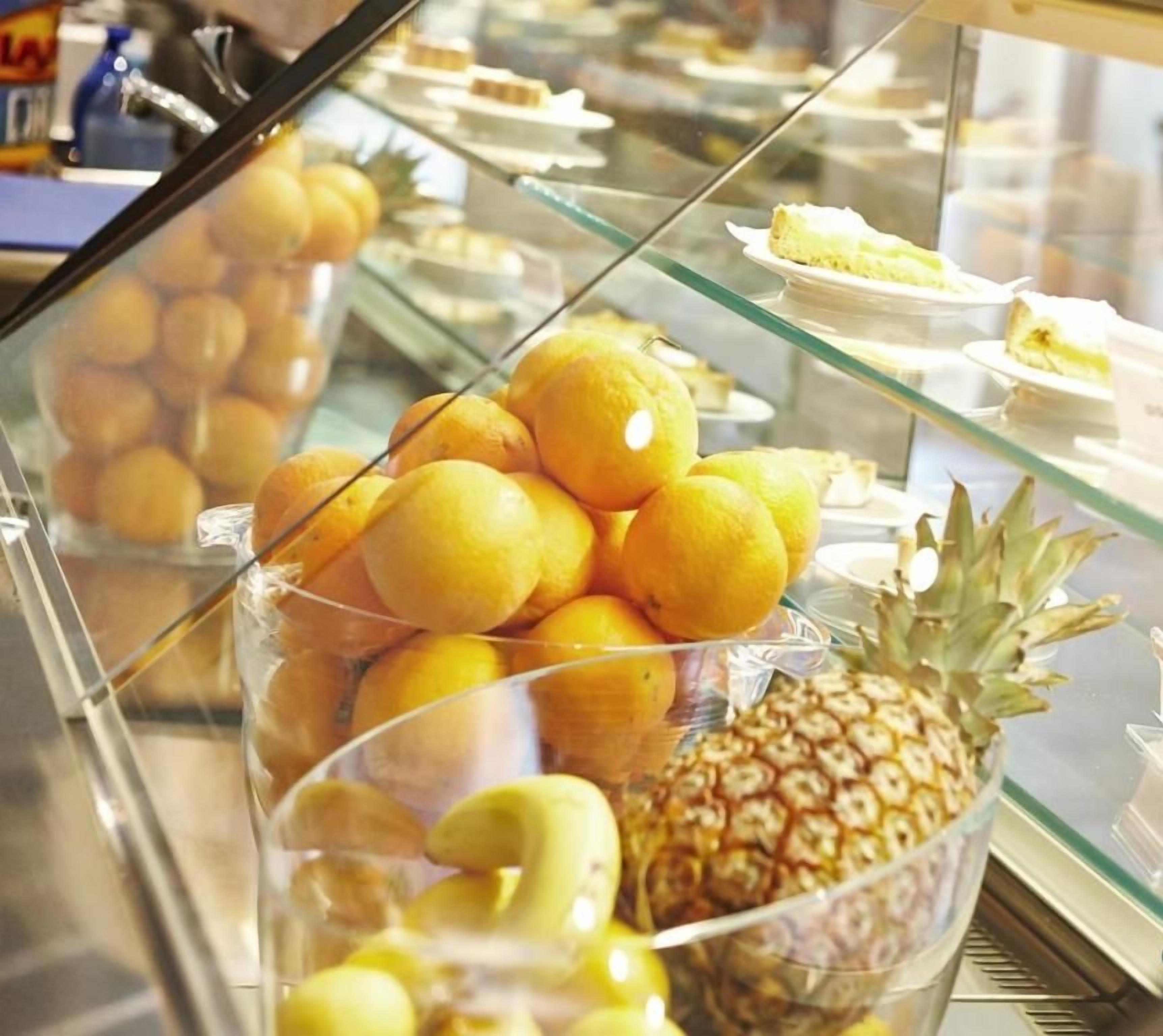 Une vitrine contenant des oranges et un ananas.