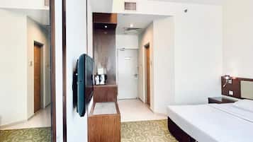 A hotel room with a bed, a desk, a television, and a mirror.