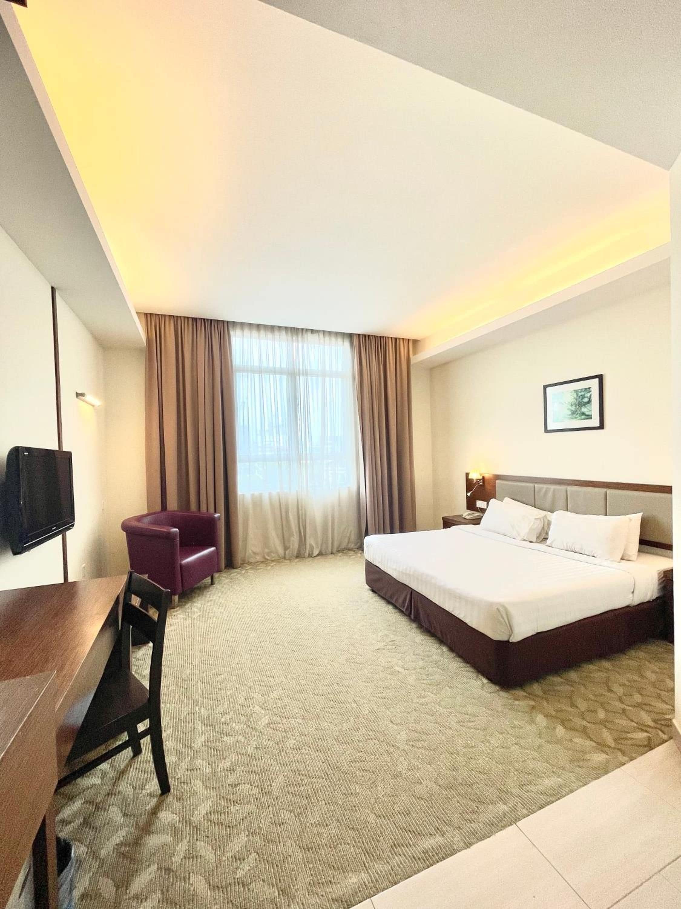 A hotel room with a bed, a desk, a chair, and a television.
