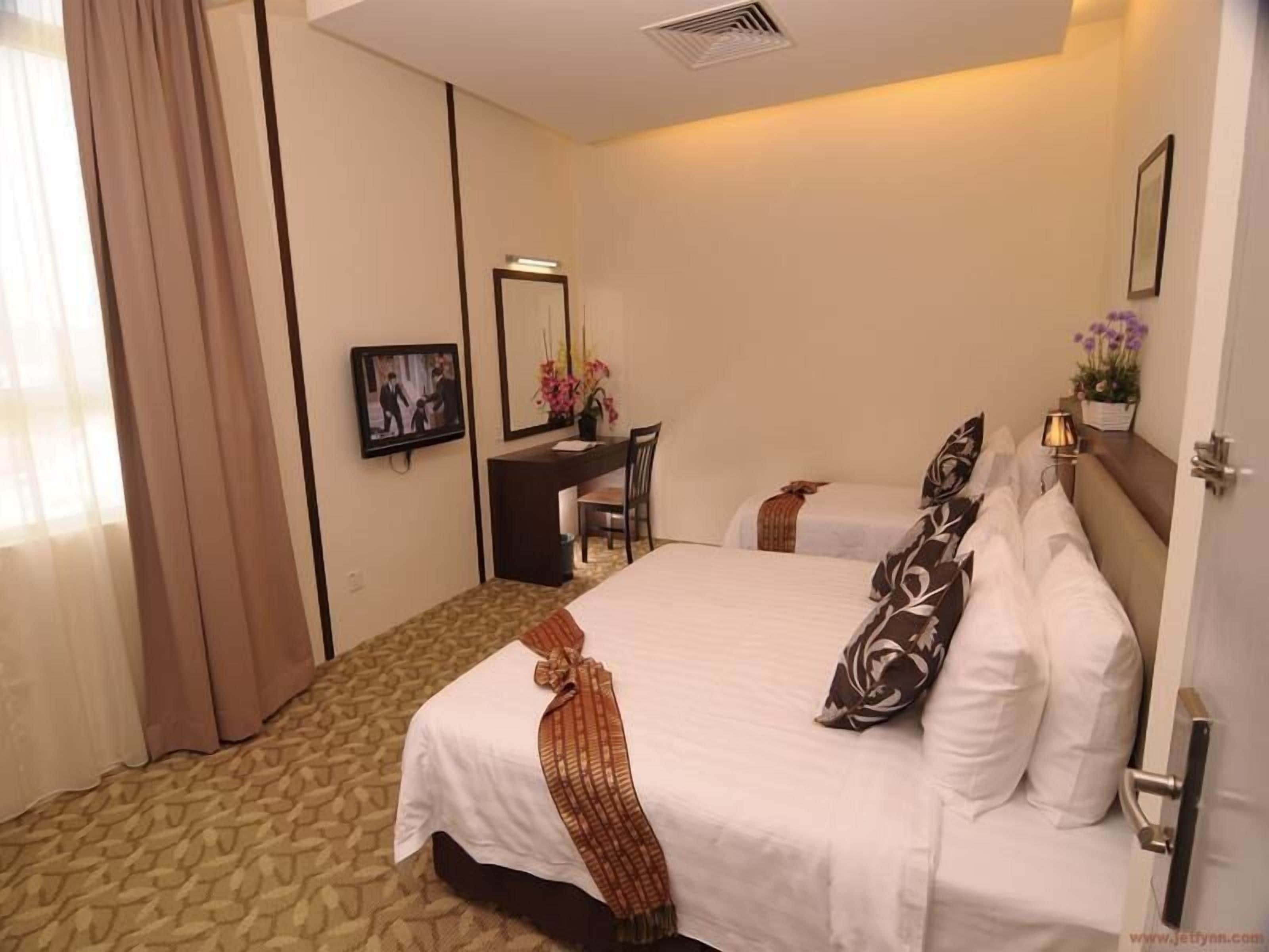 A hotel room with a bed, a desk, a chair, and a mirror.