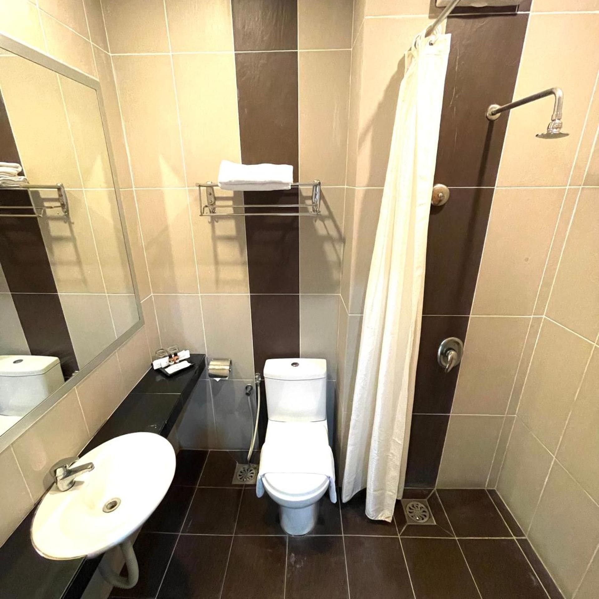 A small bathroom with a sink, toilet, and shower.