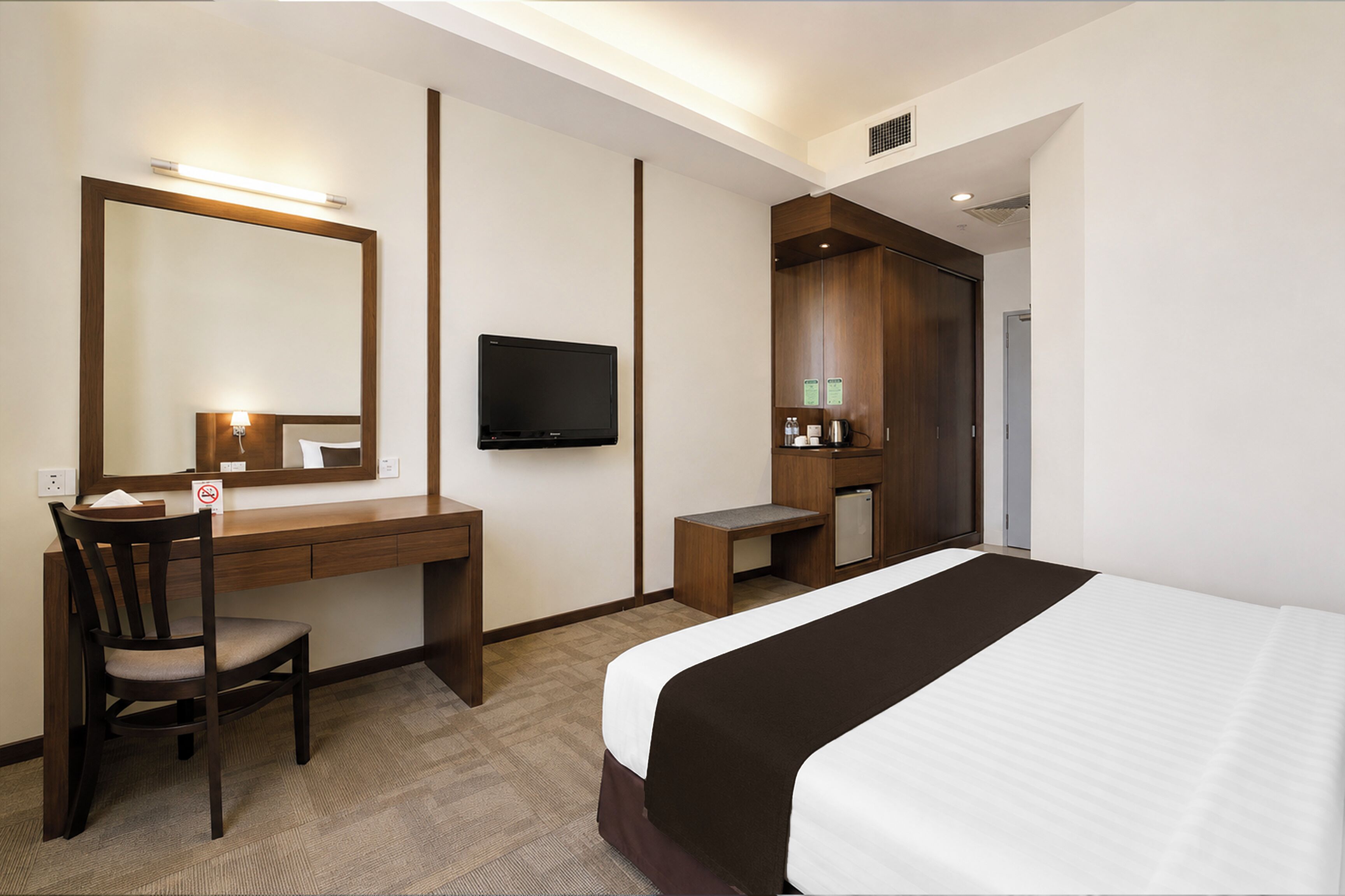 A hotel room with a bed, a desk, a chair, a television, and a wardrobe.