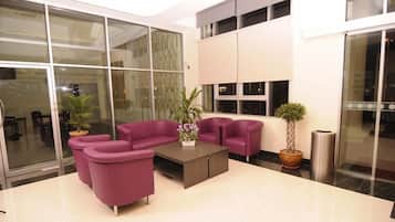 A modern lobby with a seating area, a coffee table, and potted plants.