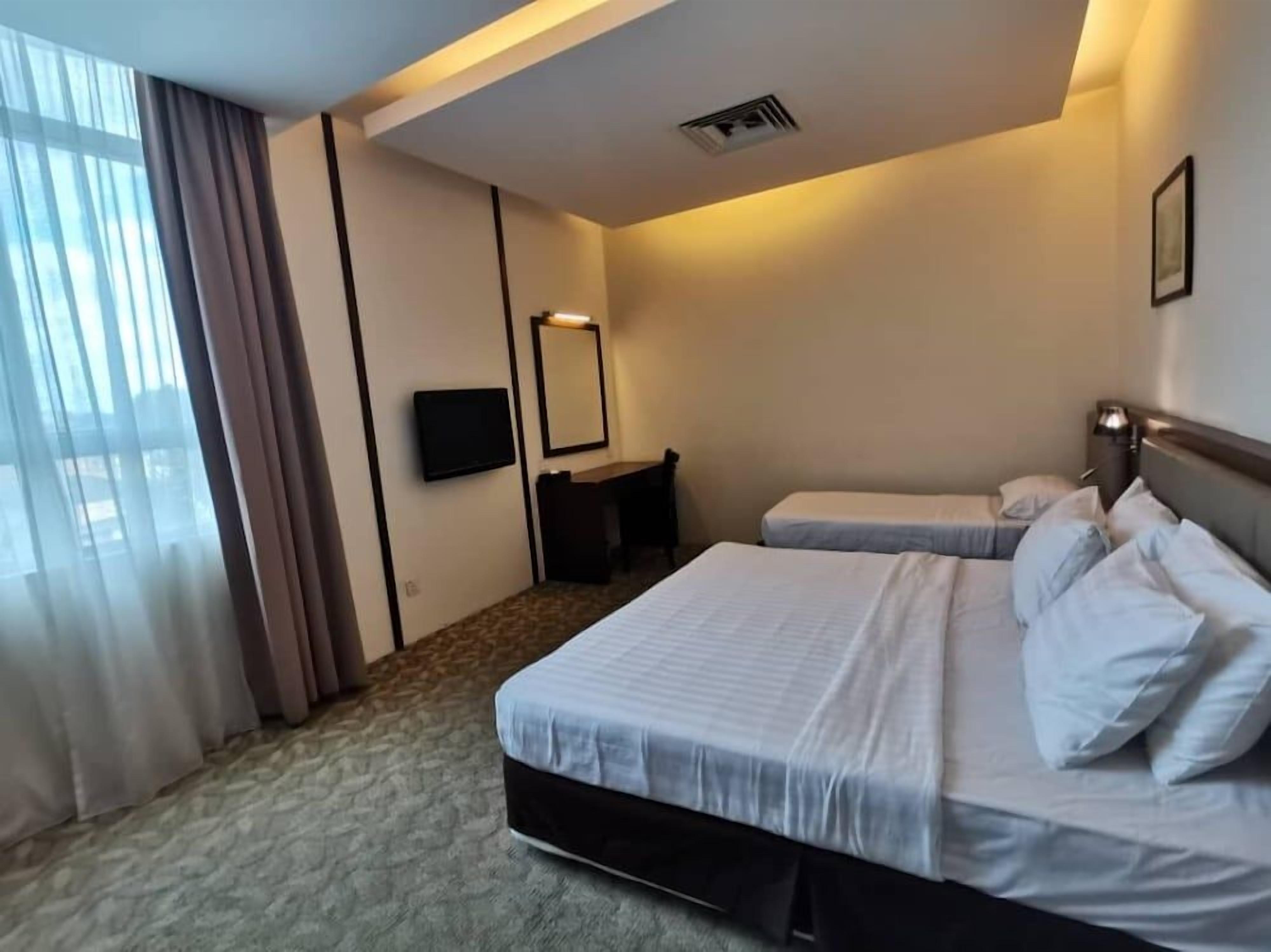 A hotel room with two beds, a desk, a chair, a television, and a large window with curtains.