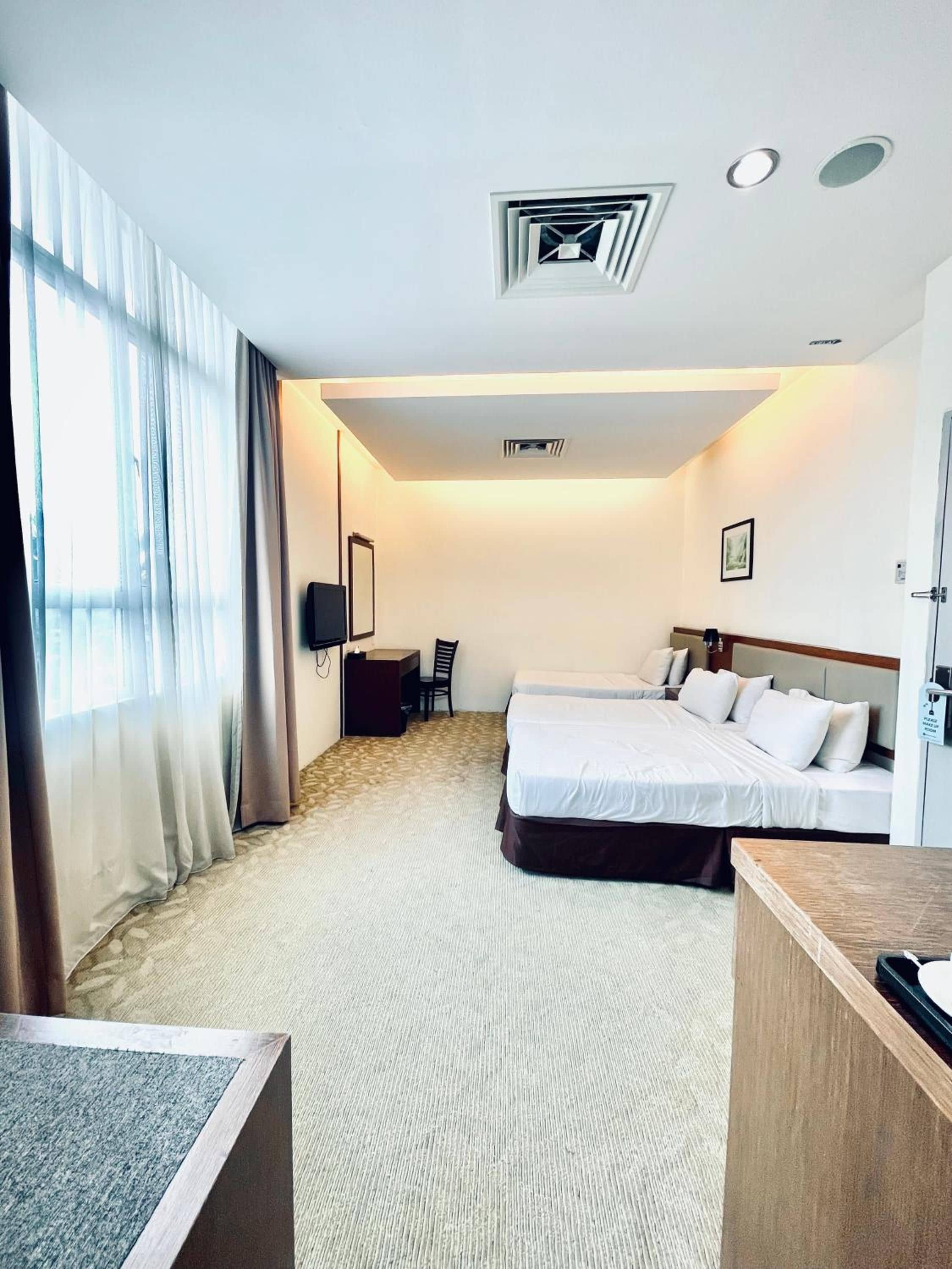 A hotel room with a bed, a desk, a chair, a TV, and a door.