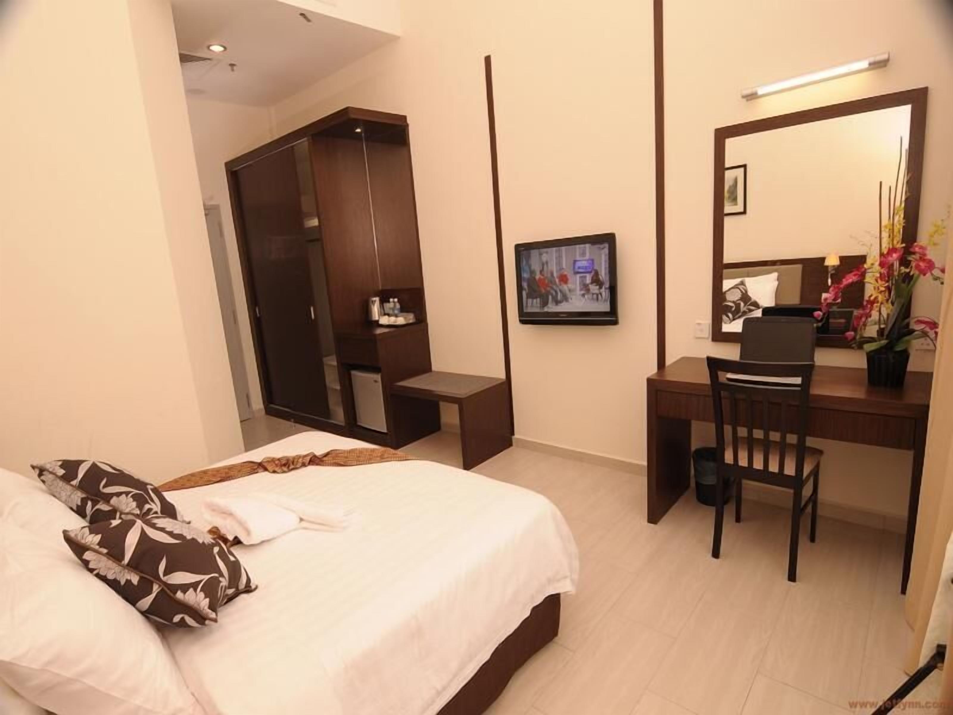 Habitación de hotel con cama, escritorio, silla, armario y televisor.