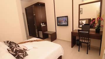 A hotel room with a bed, a desk, a chair, a wardrobe, and a television.