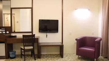 A hotel room with a desk, chair, television, and a small table.