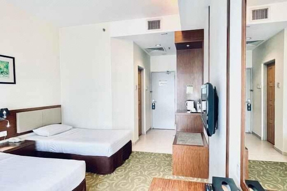 A hotel room with a bed, a desk, a television, and a small kitchenette area.