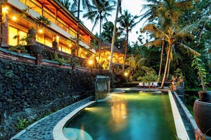 A resort with a swimming pool, lounge chairs, and a stone wall.