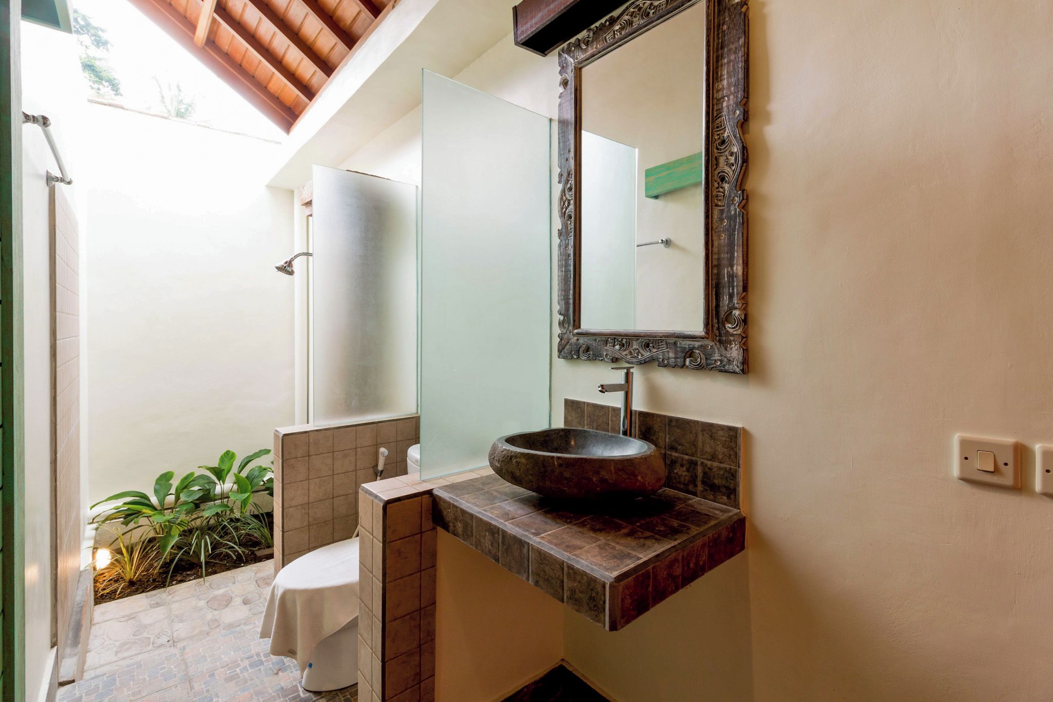 A bathroom with a stone sink, a mirror, and a toilet.