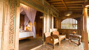 A wooden room with a bed, a chair, and a table. - Umasari Rice Terrace Villa (Mengwi)