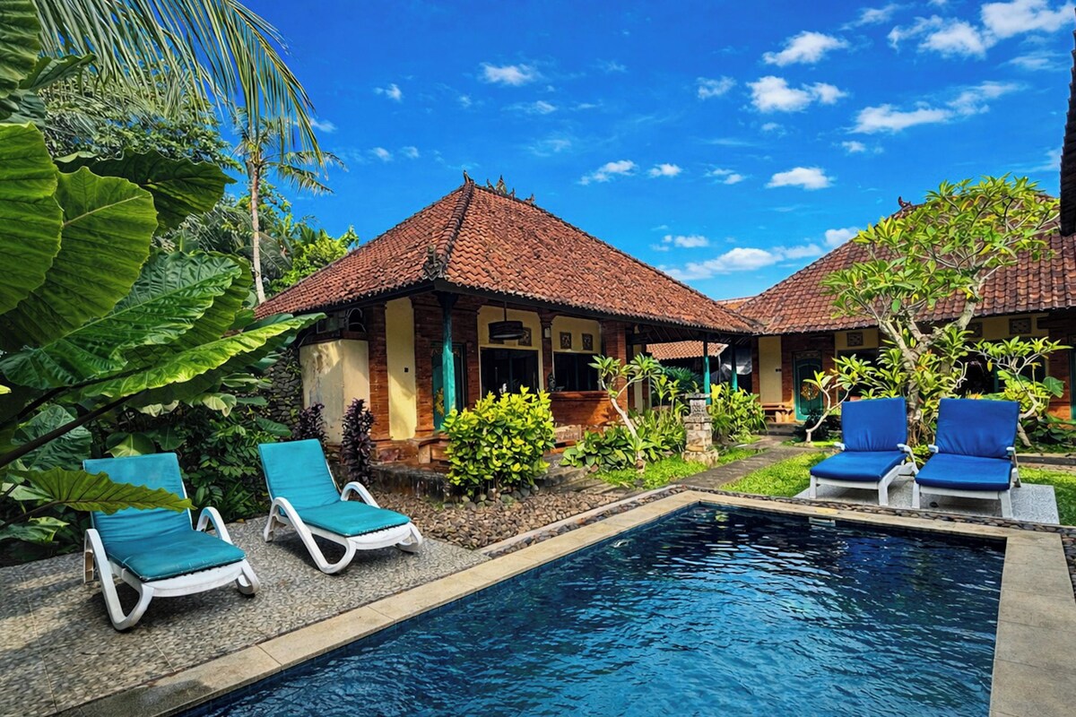 Zona junto a la piscina con sillones de descanso y un cielo azul despejado.