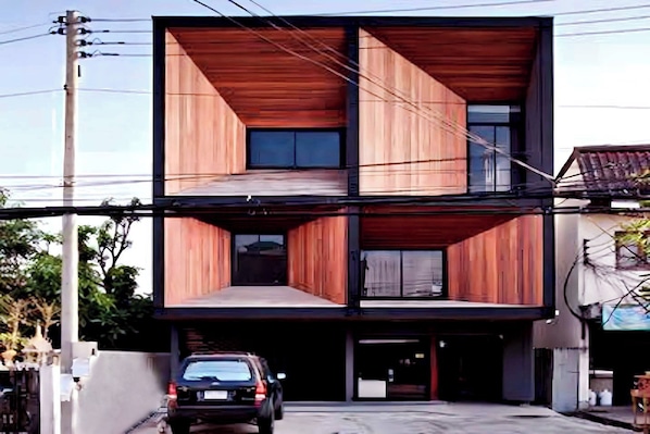 A modern two-story building with a flat roof, large windows, and a car parked in front. - HeyHa House ChiangMai (Chiang Mai)