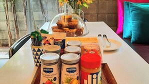 A breakfast tray with various spreads and a glass of juice on a table with a window view. - HeyHa House ChiangMai (Chiang Mai)