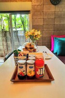 Bandeja de desayuno con diversas mermeladas y un vaso de jugo sobre una mesa con vista a la ventana.