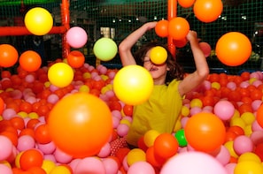 Un enfant joue dans une piscine à balles remplie de balles de toutes les couleurs.